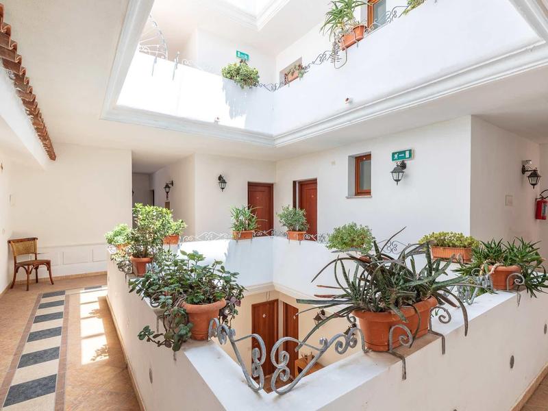 Bright hotel atrium with potted plants and tiled flooring.