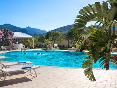 Clear swimming pool with sunshade and loungers in sunny mountain landscape