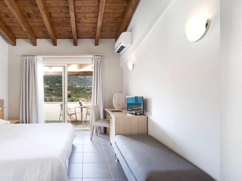 Bright hotel room with wooden beam ceiling, double bed, TV, and balcony with view.