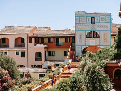Meerlaagse hotelgebouw in een mediterrane, weelderige omgeving met terracotta daken.