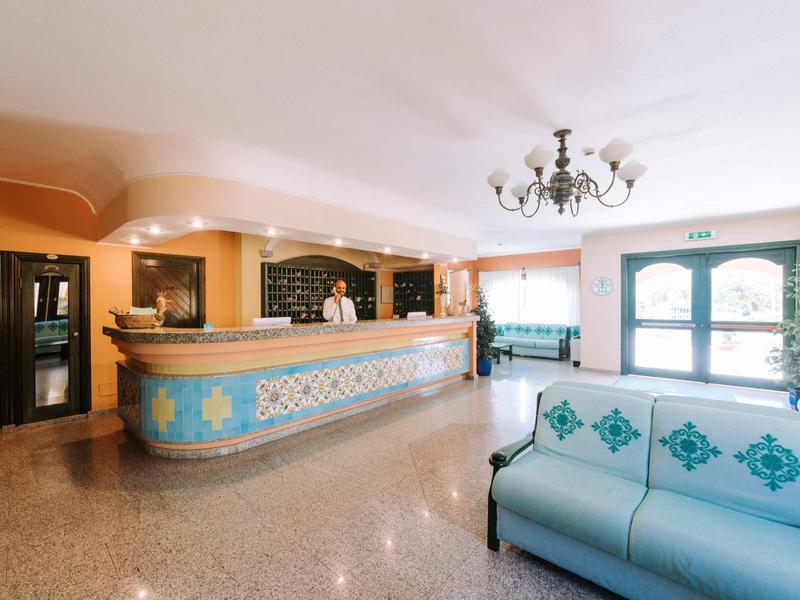 Helle Empfangshalle mit großer, verzierten Rezeption und blauem Sofa mit Blumenmuster.