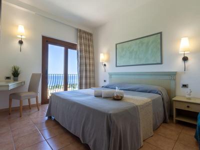 Camera d'hotel moderna con letto matrimoniale, scrivania e balcone con vista mare.