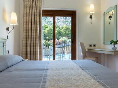 Camera d'hotel accogliente con letto grande, balcone e vista sulla natura verde