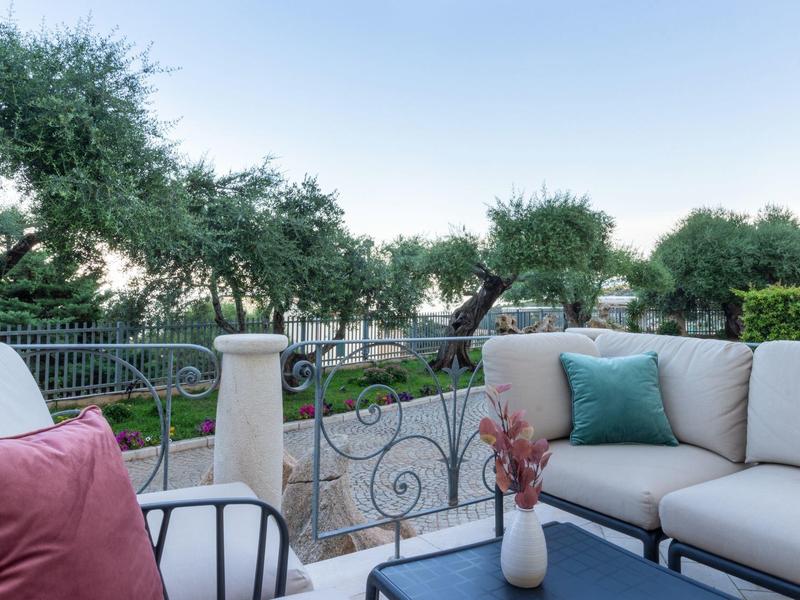 Accogliente terrazza con mobili da giardino e vista su ulivi sotto un cielo limpido.