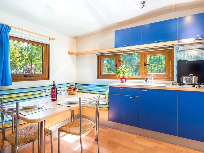 Cuisine moderne avec armoires bleues, plans de travail en bois et grande fenêtre donnant sur la verdure.