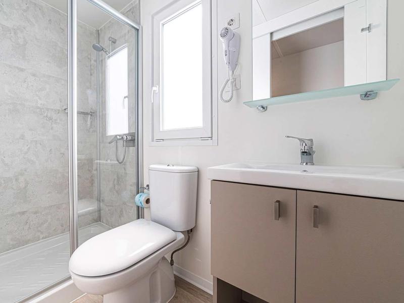 Salle de bains moderne avec douche, toilettes et lavabo aux couleurs claires.