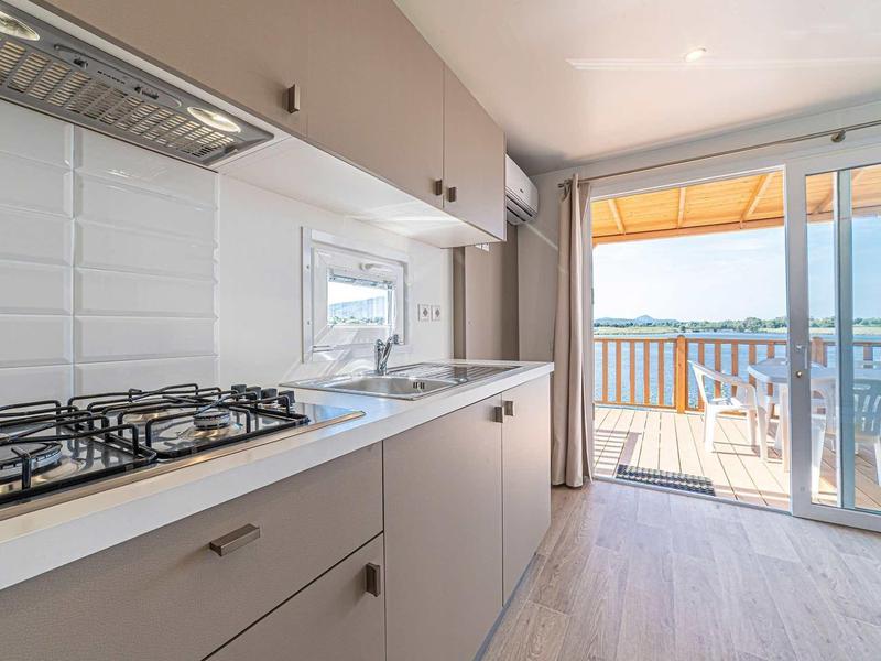 Cuisine moderne avec cuisinière à gaz, évier et accès au balcon avec vue sur le lac.