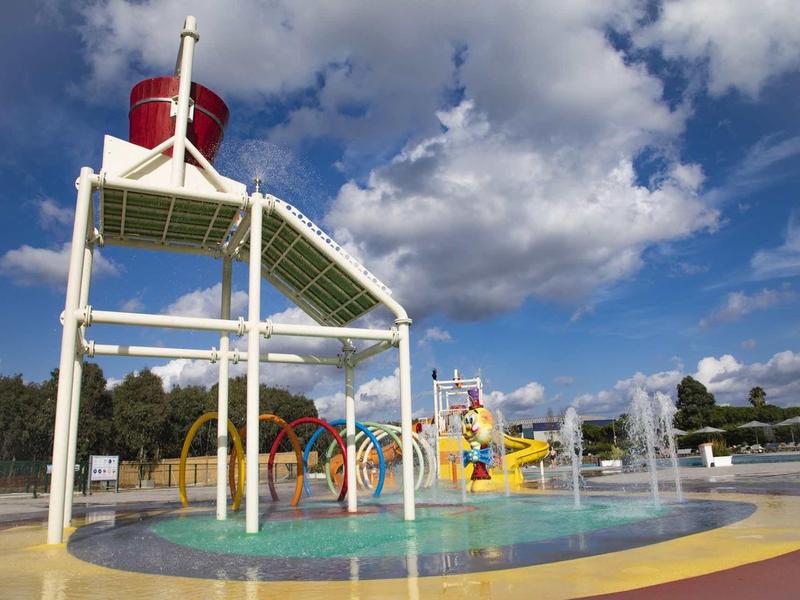 Aire de jeux aquatique colorée avec toboggans et jets d'eau sous un ciel bleu.