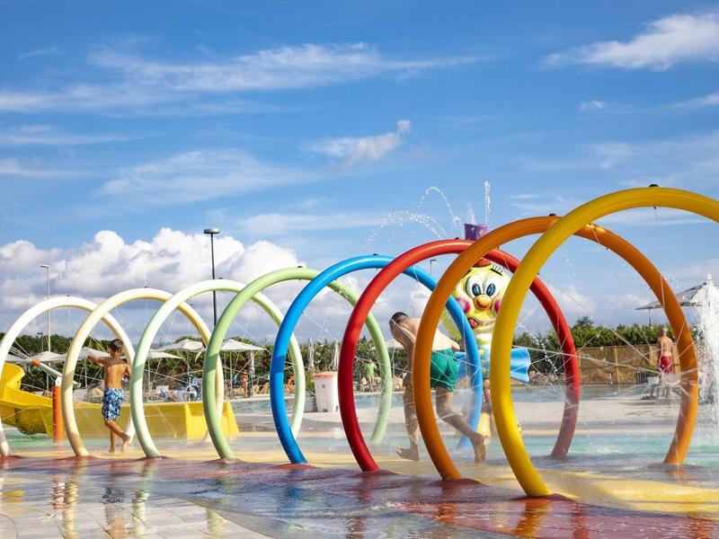 Arches colorées d'aire de jeux aquatique sous un ciel bleu dans un centre de loisirs.
