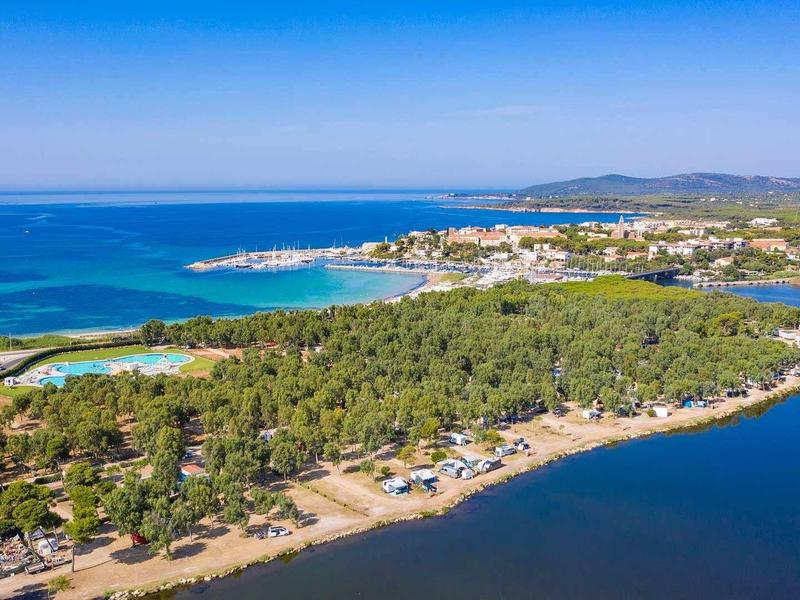 Ville côtière avec plages, forêts et mer bleue sous ciel clair.
