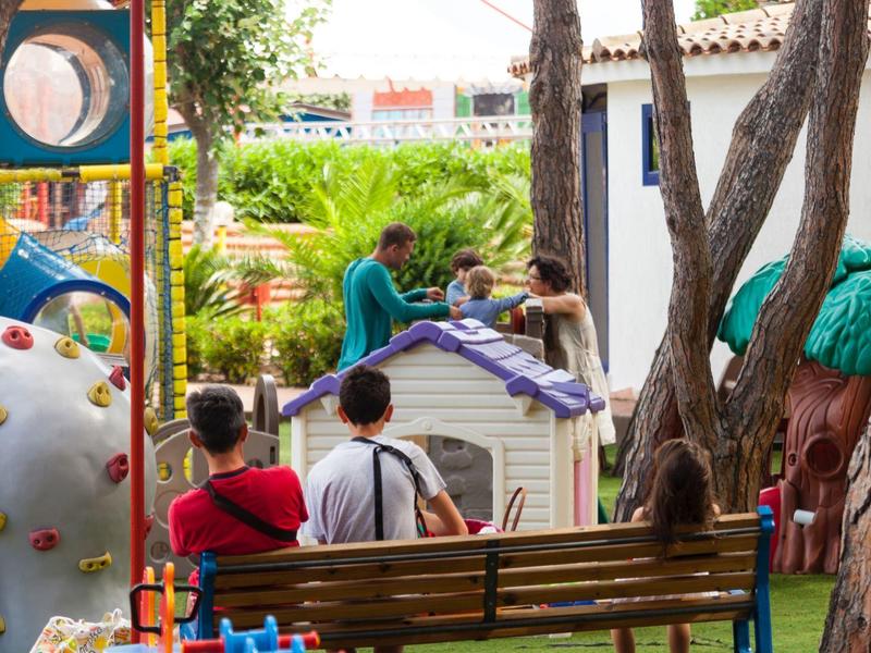 Kinder spielen auf einem bunten Spielplatz mit Rutsche und Kletterwand im Freien.