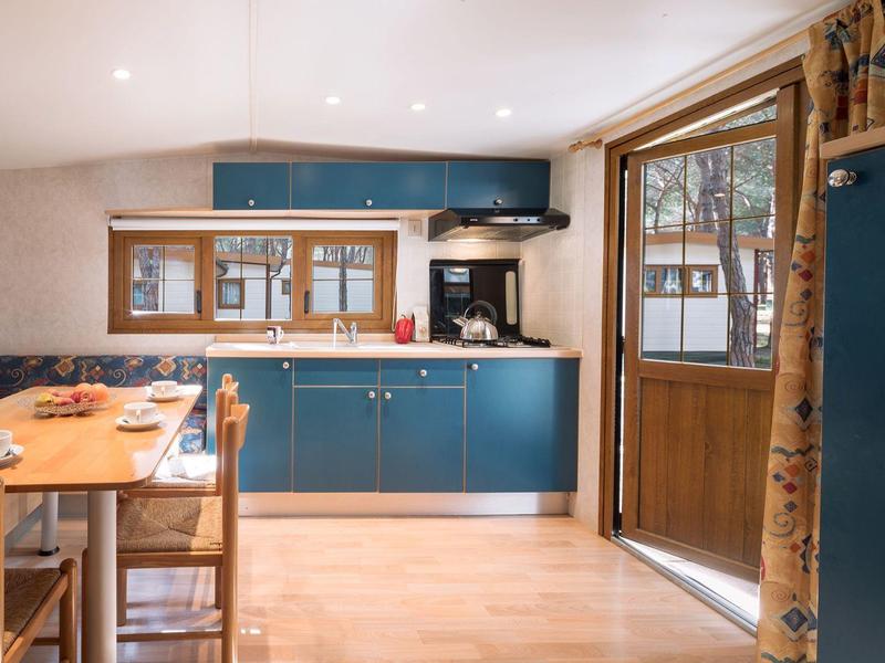 Moderne Küchenzeile in blau mit Holztisch und großen Fenstern in einem gemütlichen Raum.