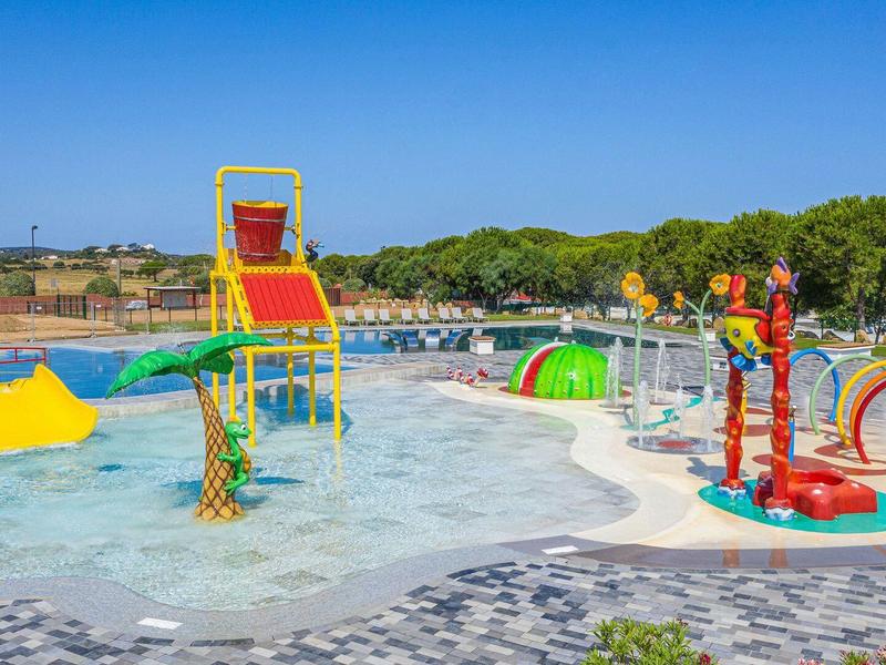 Bunter Wasserspielplatz mit Rutschen und Wasserspritzspielen unter blauem Himmel.