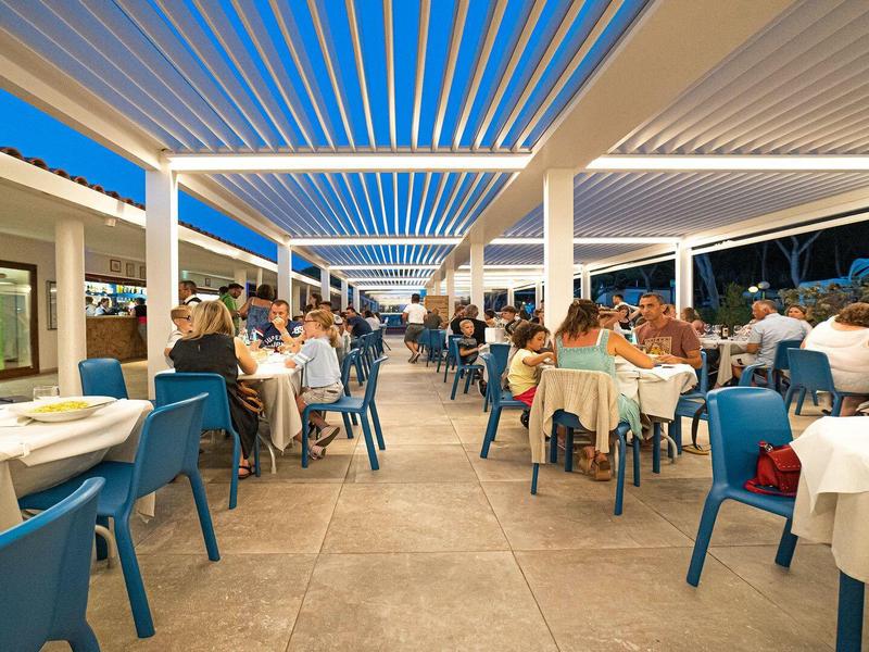 Belebtes, überdachtes Terrassenrestaurant mit Gästen bei Nacht und moderner Beleuchtung.