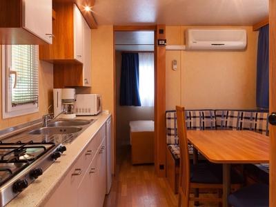 Příjemný interiér rekreačního domu s kuchyní, jídelním stolem a spací částí v pozadí.