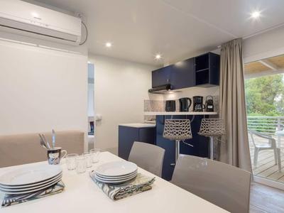 Moderní hotelová kuchyně s jídelnou a přístupem na terasu s výhledem na zeleň.