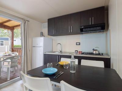 Malá kuchyň s tmavými skříňkami a jídelním stolem vedle dveří na terasu.