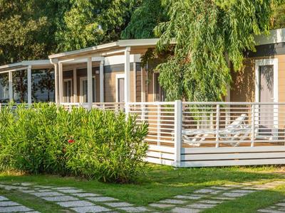 Moderní rekreační domy s verandou a lehátky v zelené zahradě