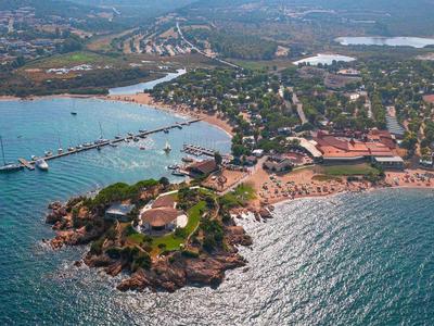 Letecký pohled na pobřežní město s molem a hotely na slunné pláži.