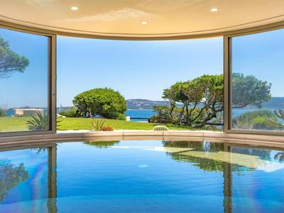 Vnitřní bazén s panoramatickým výhledem na zahradu a moře přes velká okna.