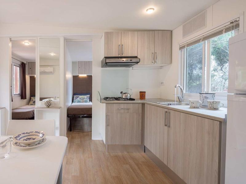 Moderní kuchyň s dřevěnými skříňkami v rekreačním domě vedle jídelny a ložnice.