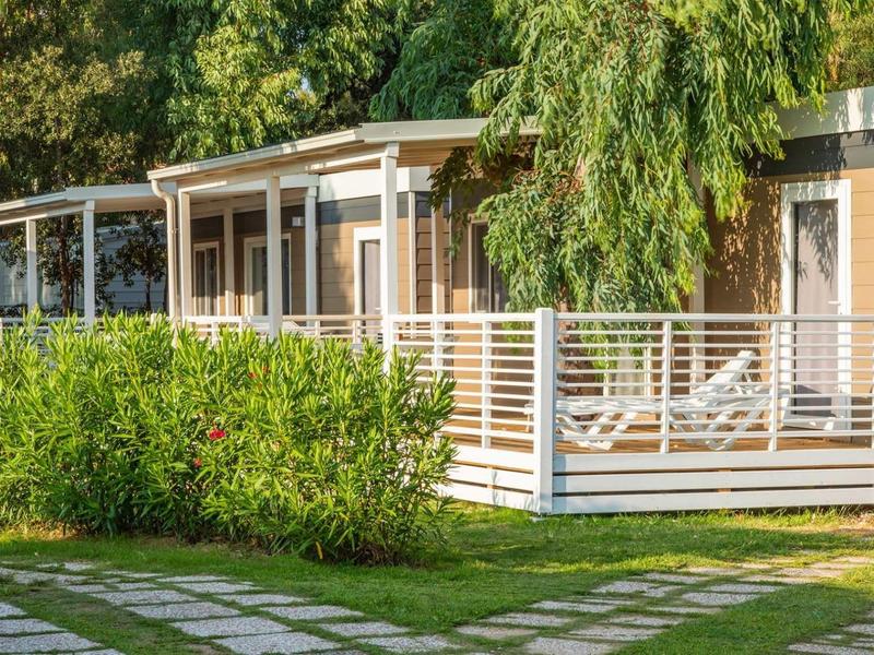 Moderní rekreační domy s verandou a lehátky v zelené zahradě