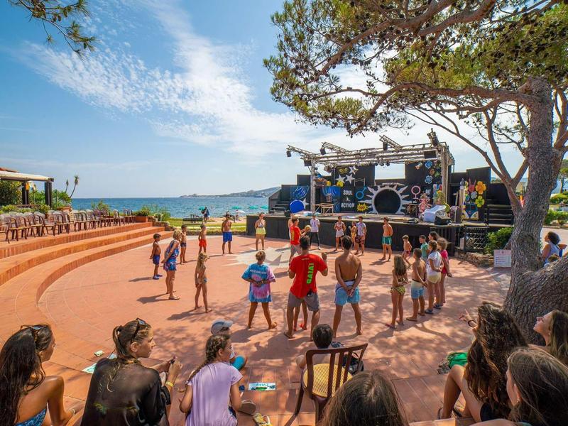 Venkovní stage u moře s lidmi shromážděnými na otevřeném prostranství za slunečného počasí.