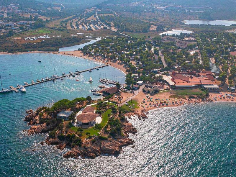 Letecký pohled na pobřežní město s molem a hotely na slunné pláži.