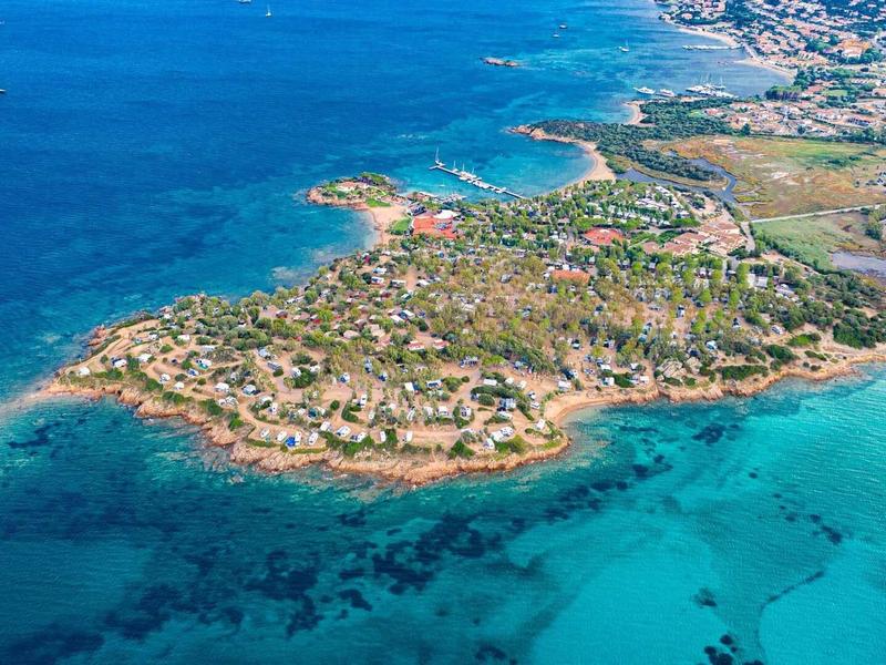 Letecký pohled na přímořské město s čistými tyrkysovými vodami a bílými písečnými plážemi.