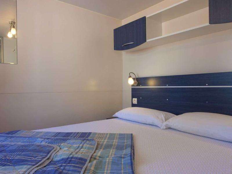 Camera accogliente con letto matrimoniale, testiera blu e copriletto a quadri.