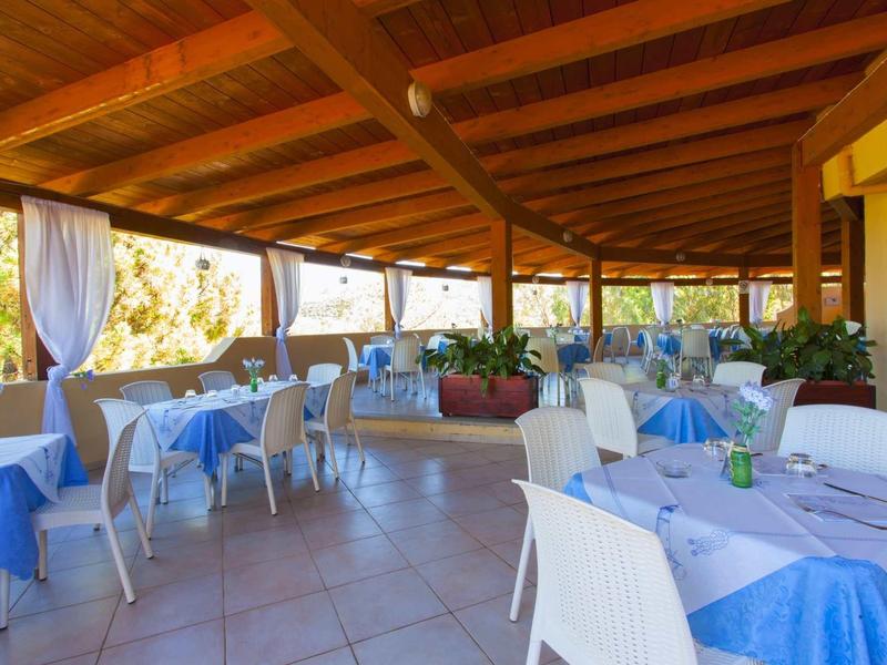 Terrazza coperta con tavoli apparecchiati e tovaglie blu in un ristorante.