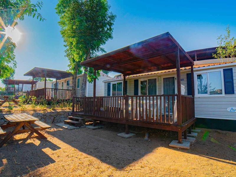 File di bungalow con balconi in legno sotto un cielo azzurro limpido con il sole.