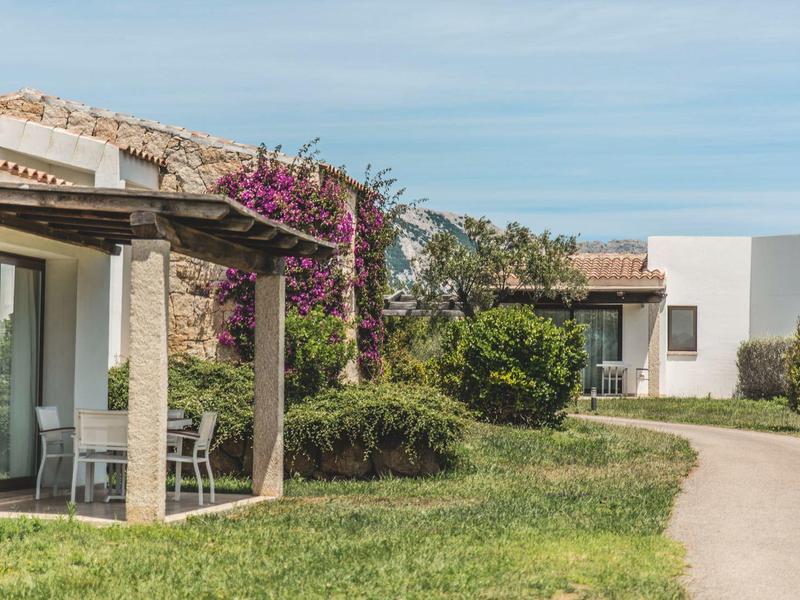 Edifici moderni bianchi con pergolati e giardino lungo una strada sotto un cielo limpido