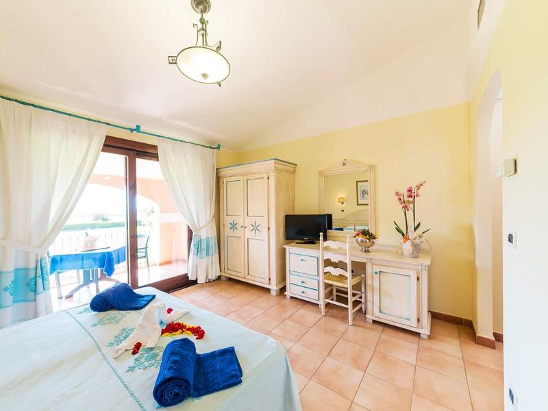 Helles Schlafzimmer mit Doppelbett, hellem Holzschrank, Kommode, Terrassentür und beige gefliesten Boden.