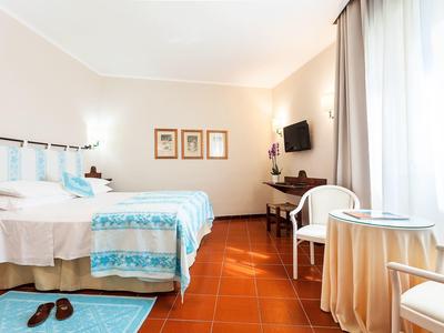 Jasny pokój hotelowy z dwoma łóżkami, stołem i krzesłem przy oknie.