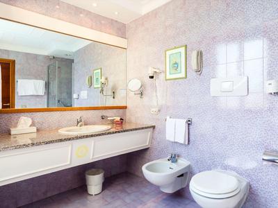 Jasna łazienka z dużym lustrem, umywalką, bidetem i toaletą.