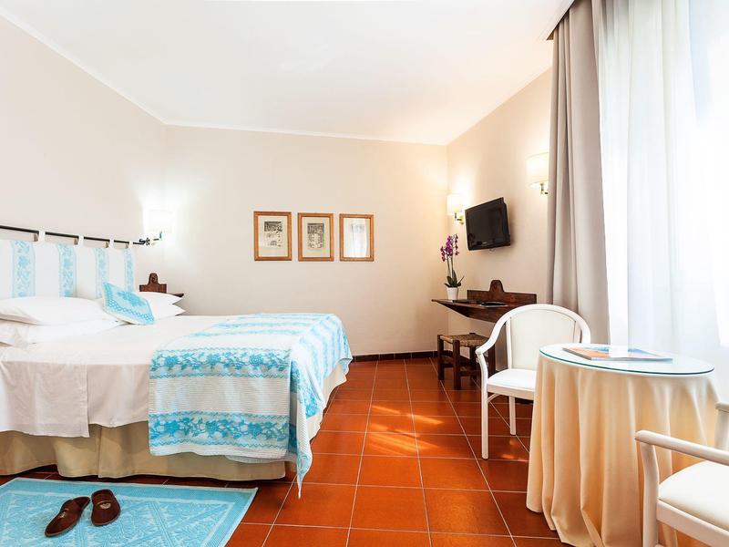 Jasny pokój hotelowy z dwoma łóżkami, stołem i krzesłem przy oknie.