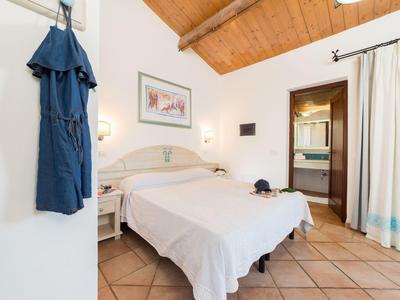 Bright hotel room with cozy double bed, wooden ceiling, and bathroom access.