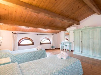 Chambre d'hôtel lumineuse avec plafond à poutres en bois, deux lits simples et armoire antique.