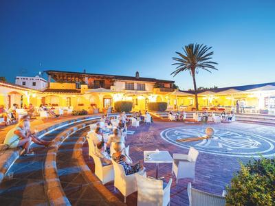 Illuminated courtyard with circular pattern and seating areas at sunset in a hotel.
