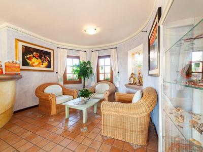 Cozy hotel lobby with round wicker chairs, white tables, and decorative elements.