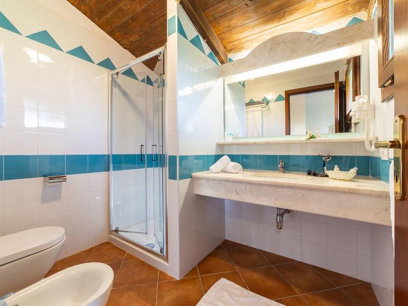 Bright bathroom with shower, toilet, and large mirror above the sink.