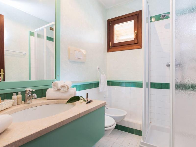Compact bathroom with shower, toilet, sink, and mirror in light colors.