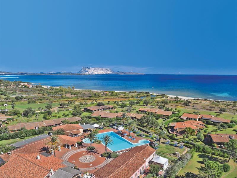 Aerial view of a resort with a pool and sea view under clear sky.