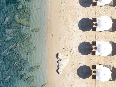 Luchtfoto van een strand met witte parasols en helderblauwe waterlijn.
