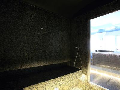 Donkere wellnessruimte met stenen bank en douche naast een raam