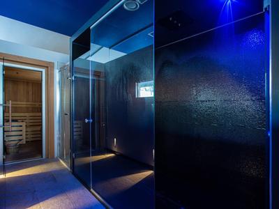 Moderne wellnessruimte met verlichte stoomkamer en aangrenzende sauna.