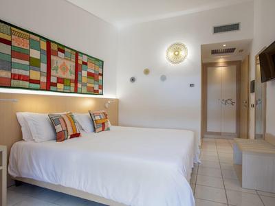 Moderne hotelkamer met twee bedden, kleurrijke kussens en minimalistische wanddecoratie.