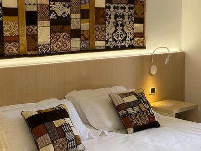 Modern hotelkamer met tweepersoonsbed, decoratieve kussens en wanddecoratie.