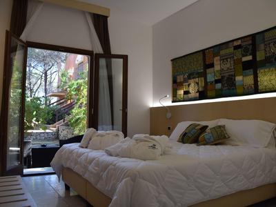 Gezellige hotelkamer met open raam naar een groene tuin.